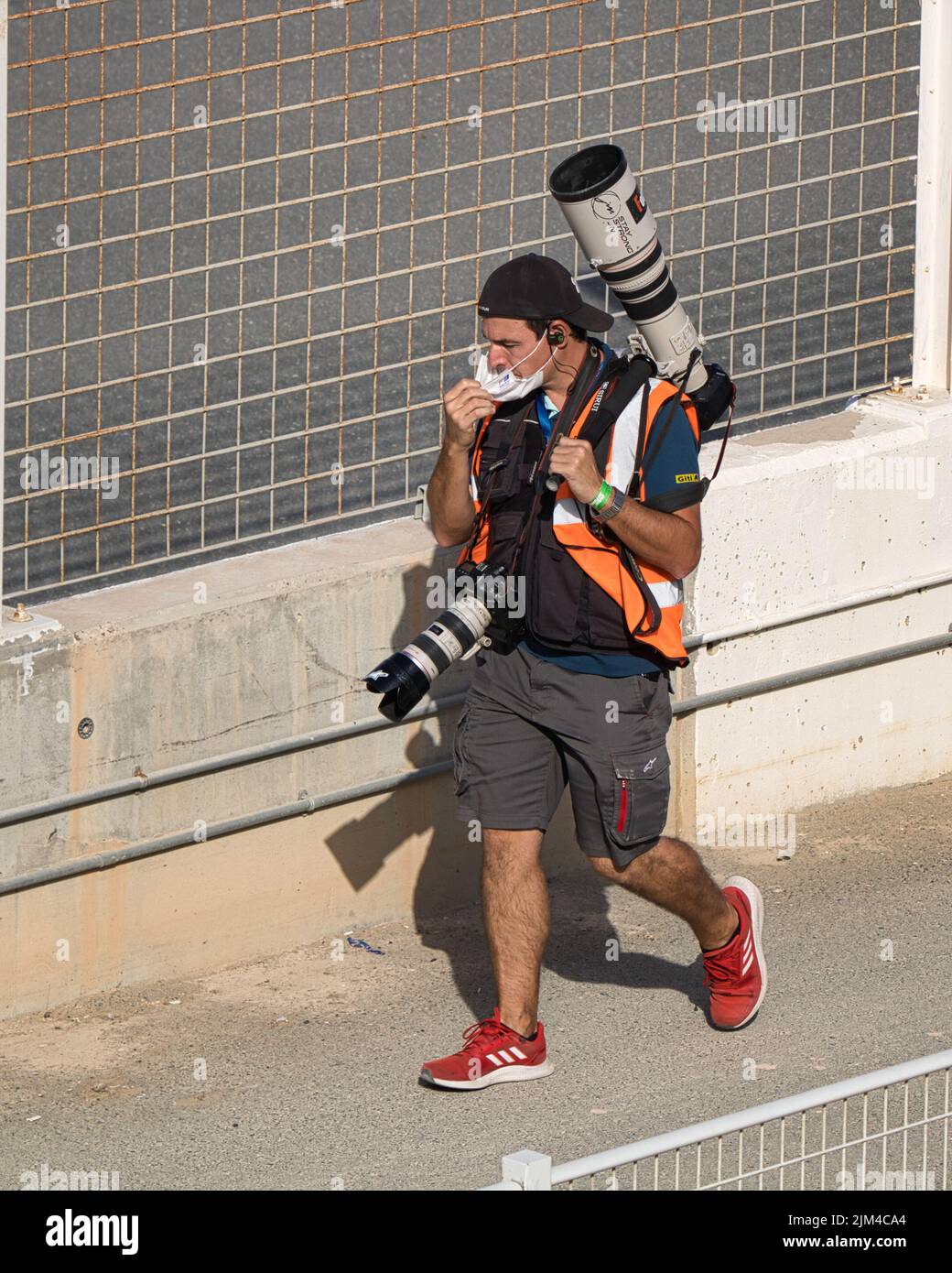 Un primo piano di un maschio con macchine fotografiche che camminano sul marciapiede dell'Autodromo di Dubai durante gli sport motoristici Foto Stock