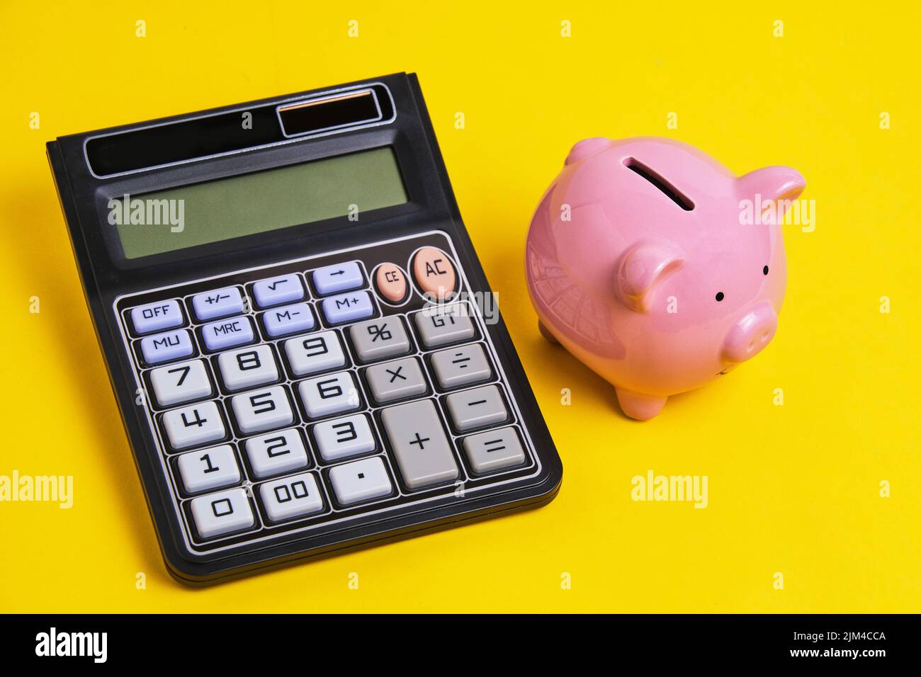 Calcolatrice e Piggy banca giallo background.Concept famiglia bilancio e business Foto Stock