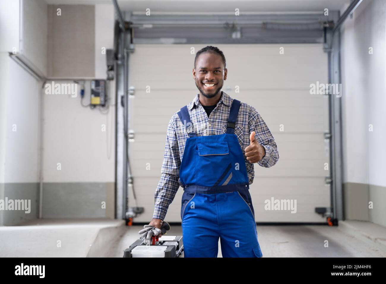 Addetto all'installazione della porta del garage. Riparazione del rullo del portellone Foto Stock