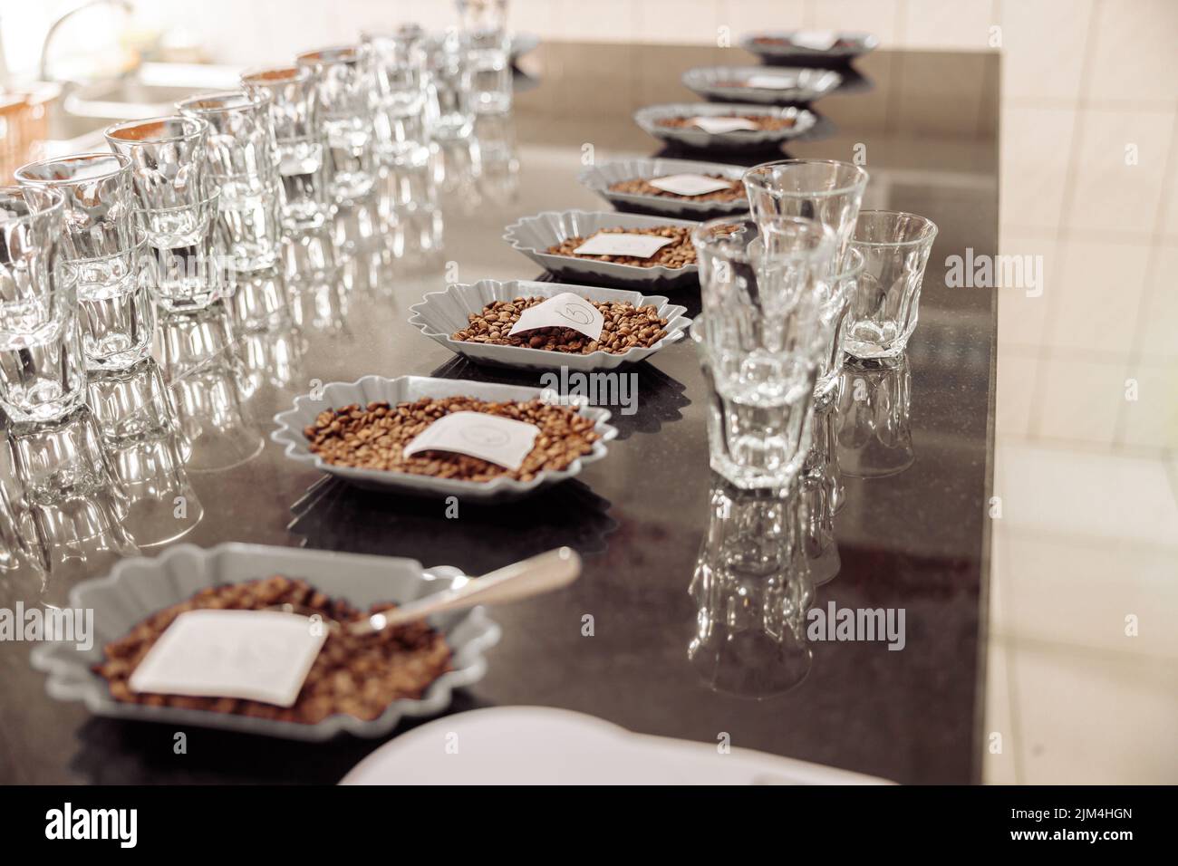 I bicchieri d'acqua vuoti si trovano vicino alle ciotole dei chicchi di caffè Foto Stock