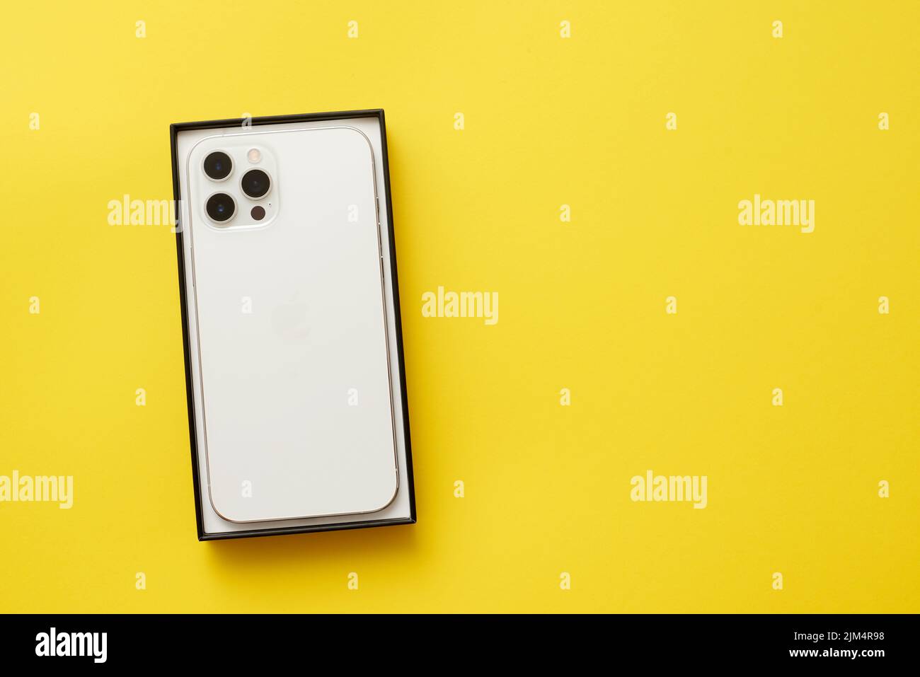 Nuovo smartphone da Apple iPhone in scatola su sfondo giallo Foto Stock