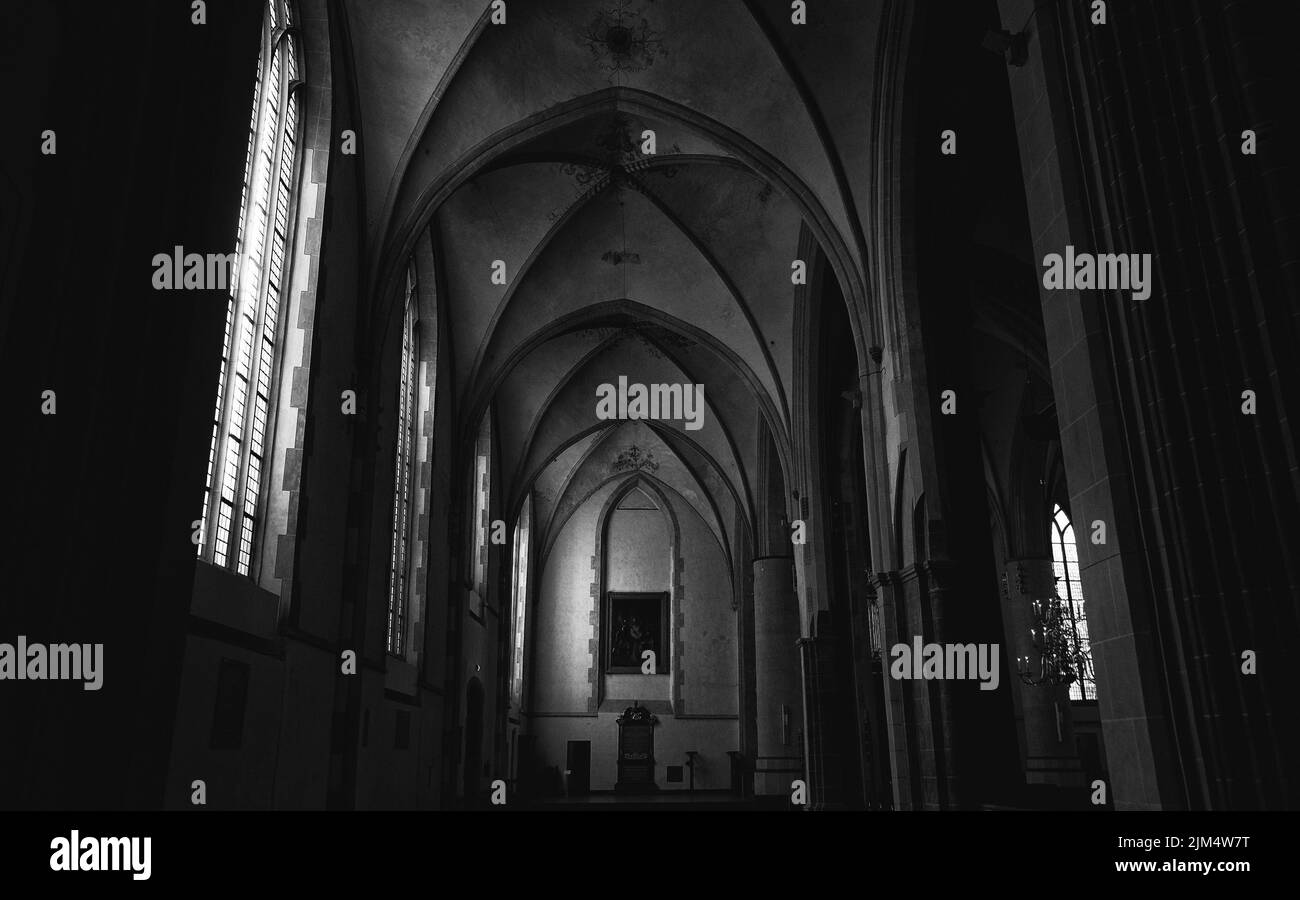 Una vista interna di un corridoio scuro di una chiesa con luce proveniente dalle finestre Foto Stock