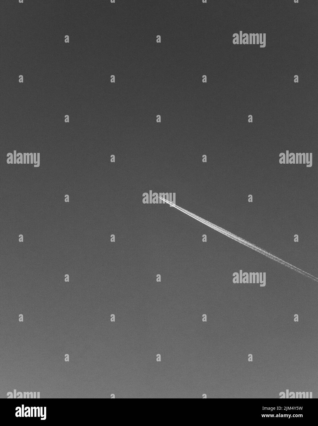 Ripresa verticale in scala di grigi di una traccia di aeroplano nel cielo Foto Stock Ripresa verticale in scala di grigi di una traccia di aeroplano nel cielo Foto Stock