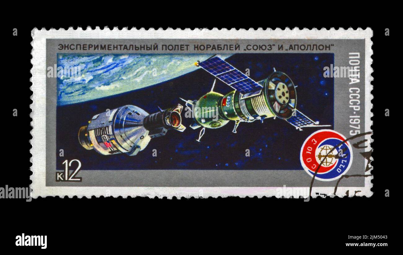 Volo sperimentale della navicella spaziale Soyuz e Apollo, circa 1975. Volo spaziale presidiato vicino al pianeta Terra.timbro post vintage isolato su sfondo nero. Foto Stock