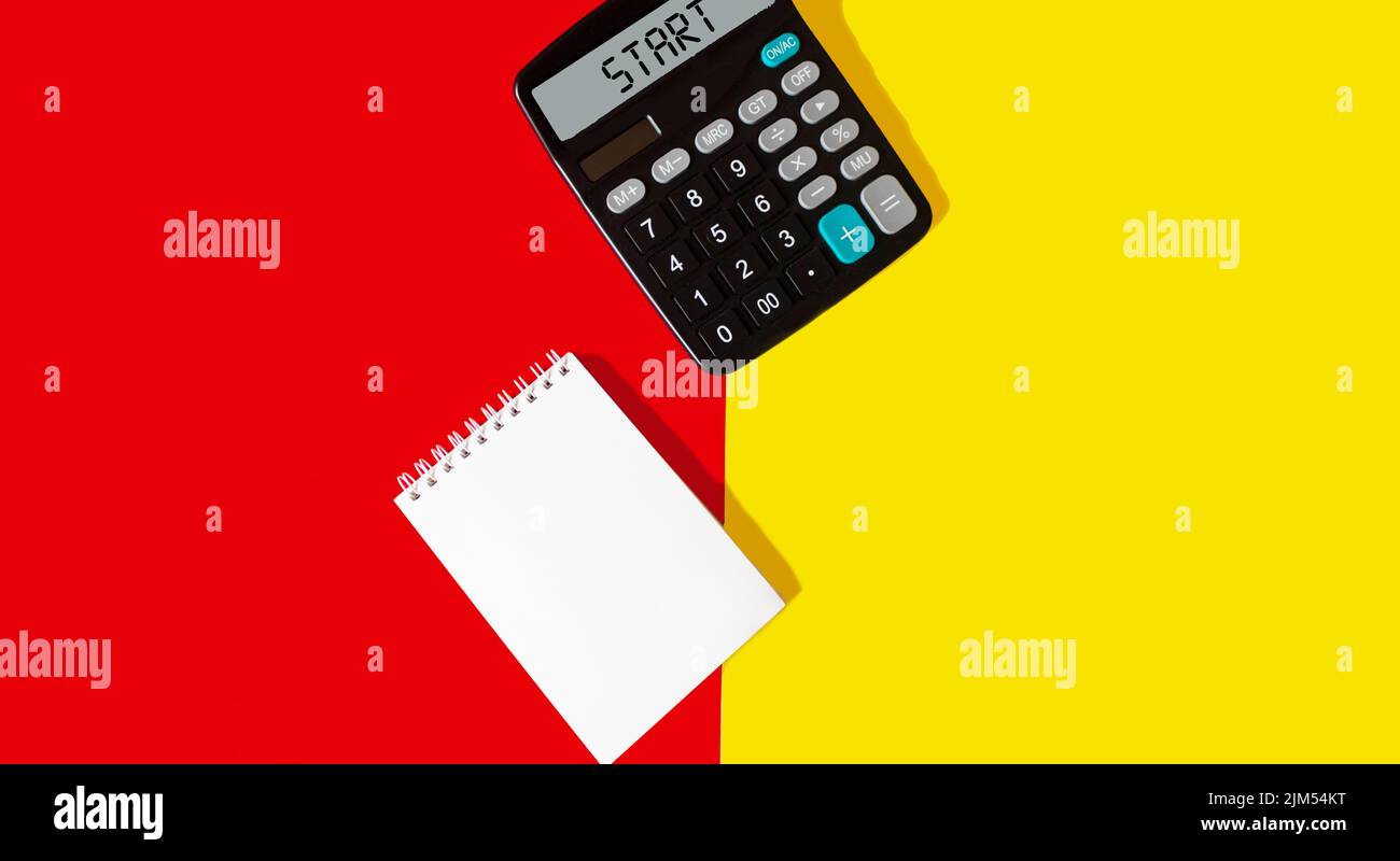 Testo iniziale sul display della calcolatrice con blocco note su sfondo giallo rosso Foto Stock
