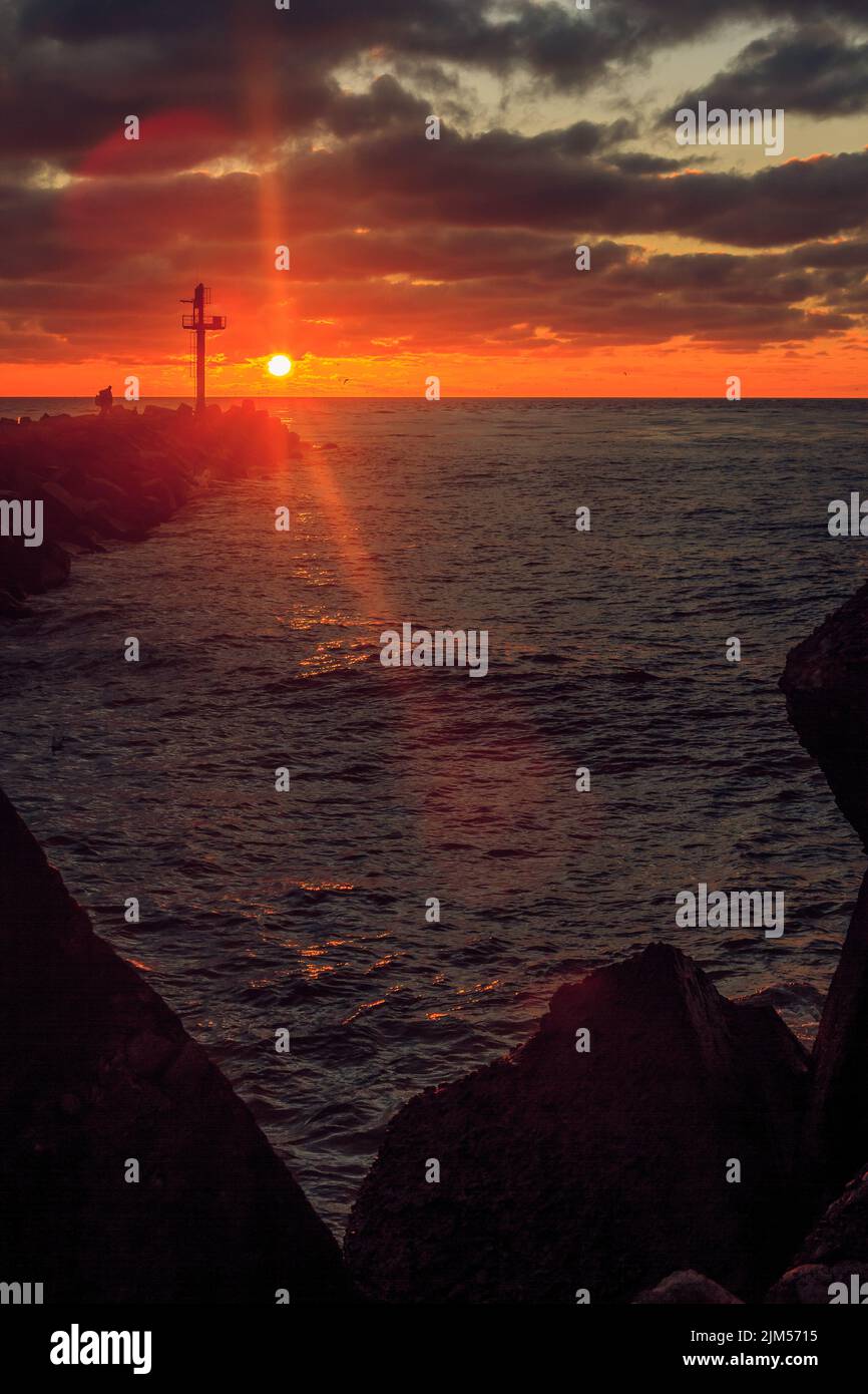 Una scena verticale del cielo rosso nuvoloso tramonto al porto di Klaipeda, Lituania con le vesti Foto Stock