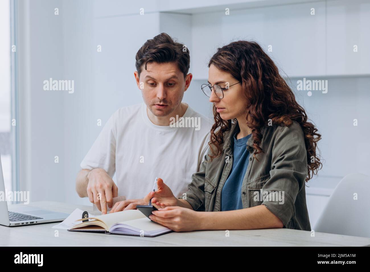 Coppia della moglie di brunette e del marito scuro-capelli che tiene il controllo del supermercato sostiene gesturing circa le spese non pianificate della famiglia dopo il calcolo Foto Stock