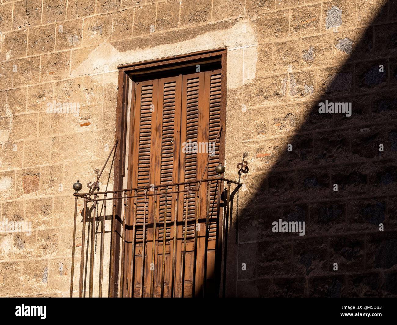 La porta in legno con una ringhiera in metallo arrugginito sotto la luce del sole. Foto Stock