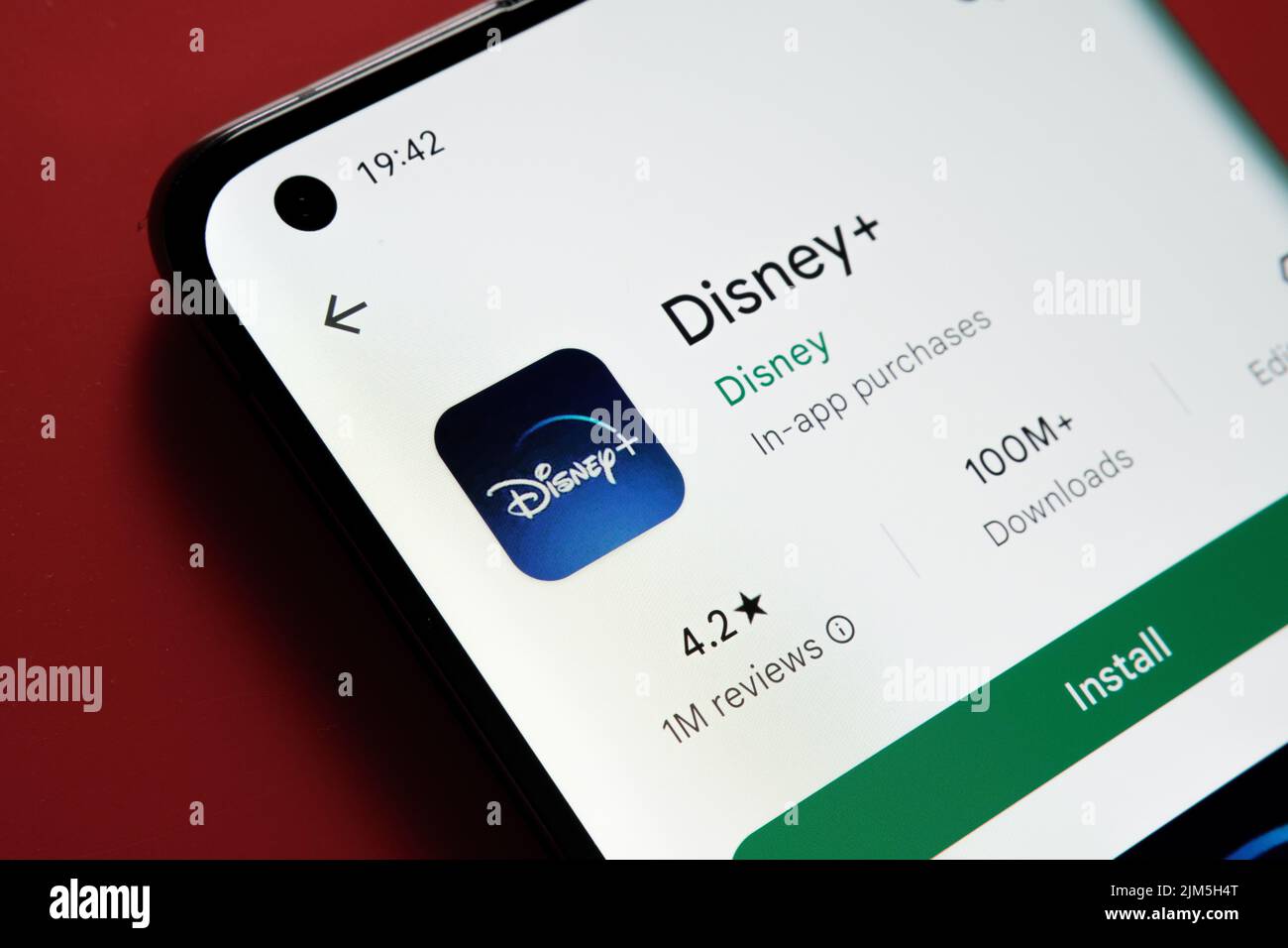App Disney Plus visualizzata in Google Play Store sullo schermo dello smartphone su sfondo rosso. Foto ravvicinata con messa a fuoco selettiva. Stafford, Regno Unito Foto Stock
