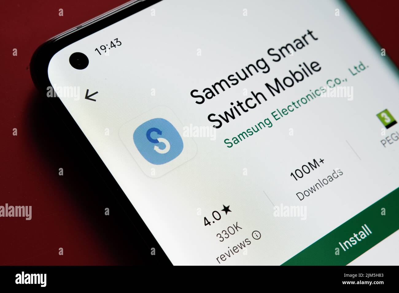 App mobile samsung Smart Switch visualizzata in Google Play Store sullo schermo dello smartphone su sfondo rosso. Foto ravvicinata con messa a fuoco selettiva. Sta Foto Stock