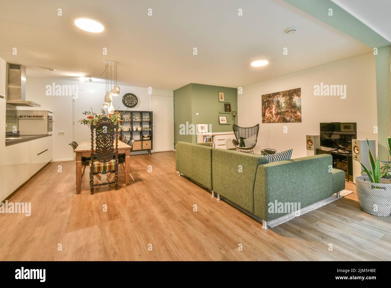 Appartamento monolocale con pareti bianche, cucina a pianta aperta e zona pranzo con divano in soggiorno Foto Stock