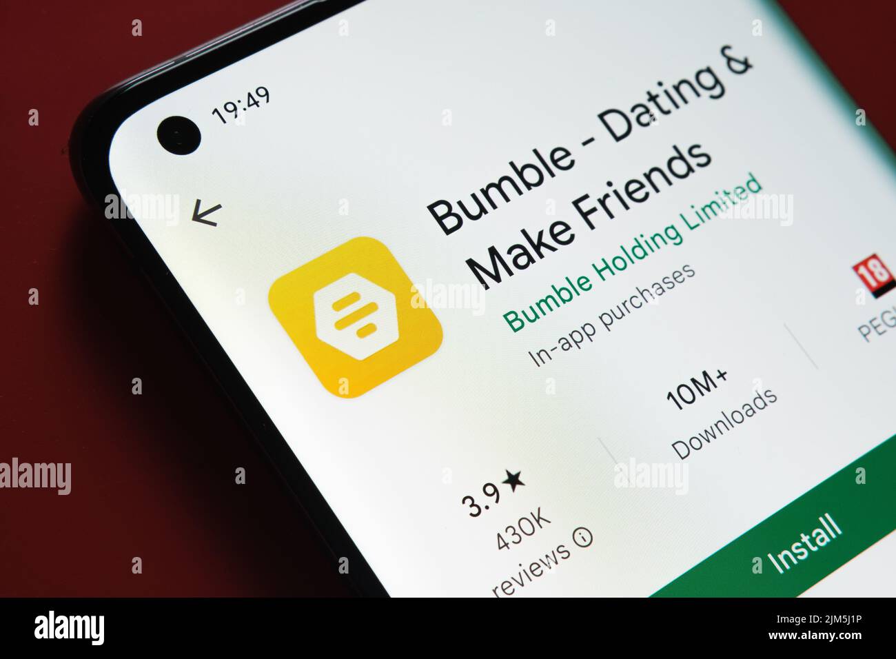 App Bumble visualizzata in Google Play Store sullo schermo dello smartphone su sfondo rosso. Foto ravvicinata con messa a fuoco selettiva. Stafford, Regno Unito, Foto Stock