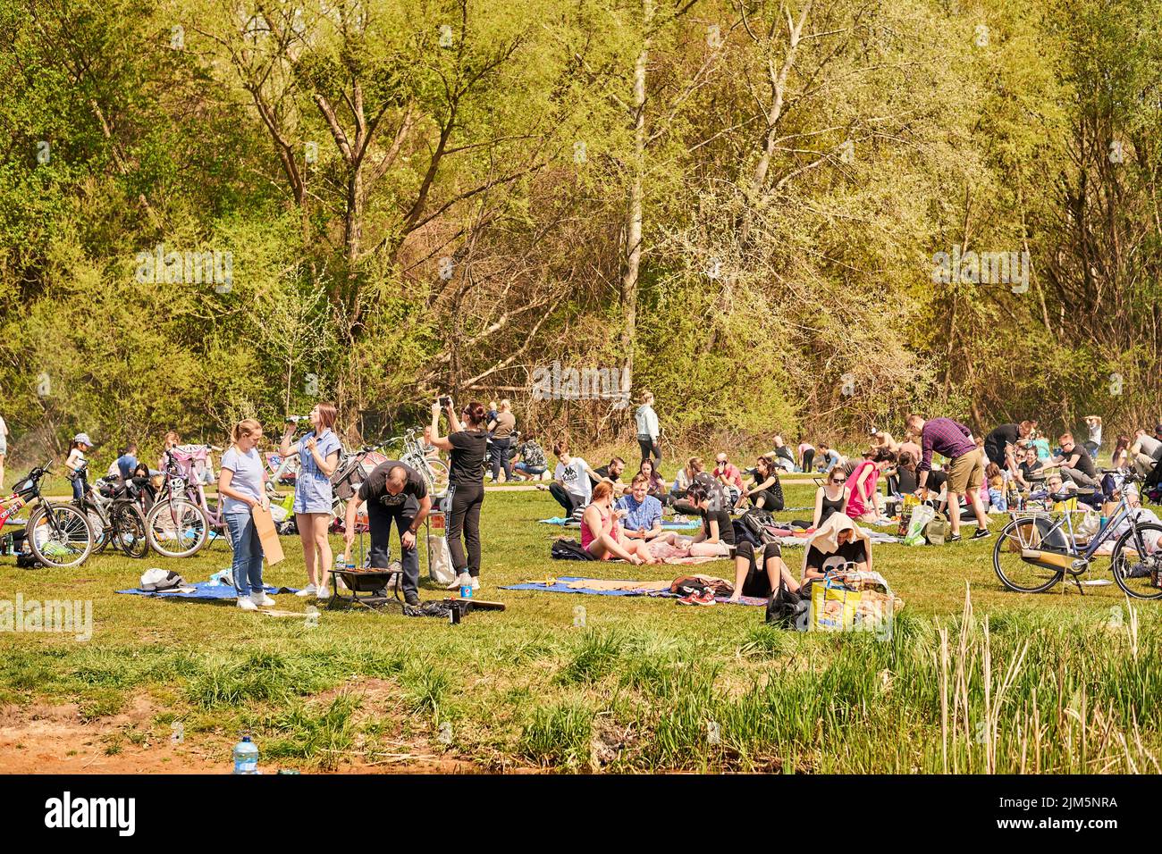 La gente che riposa sull'erba verde vicino al lago Rusalka in una giornata di primavera soleggiata Foto Stock