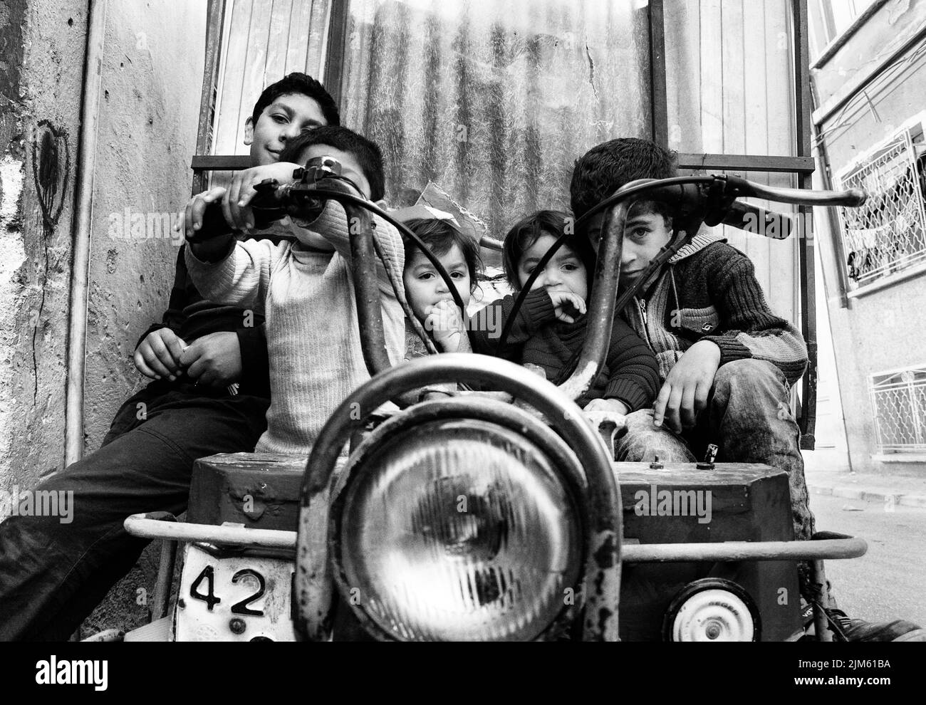 Un'immagine in scala di grigi di un gruppo di bambini seduti e che giocano su una vecchia automobile a Istanbul, in Turchia Foto Stock