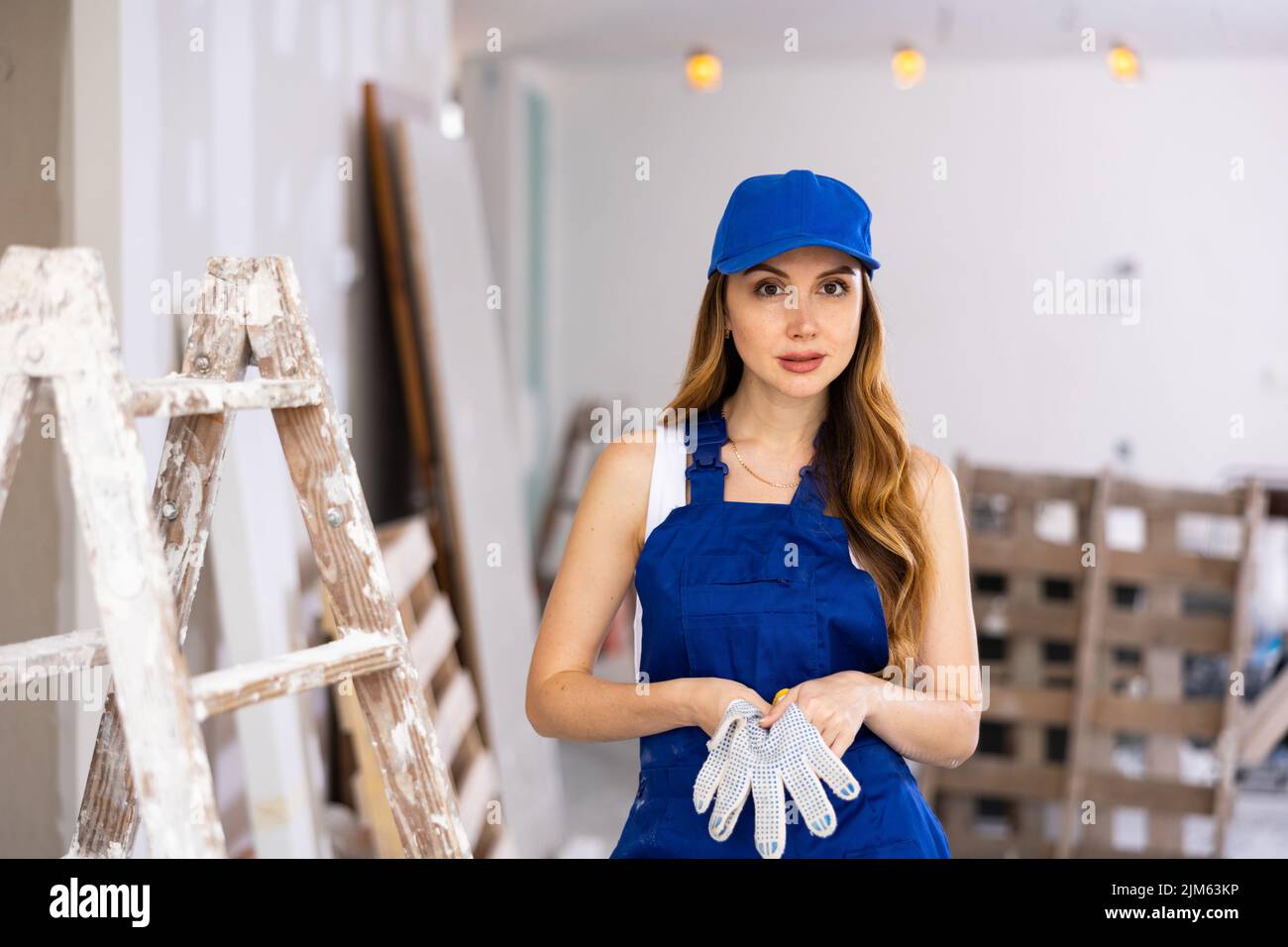 Caposquadra femmina dai capelli marroni in abiti da lavoro blu in piedi in edificio in costruzione Foto Stock