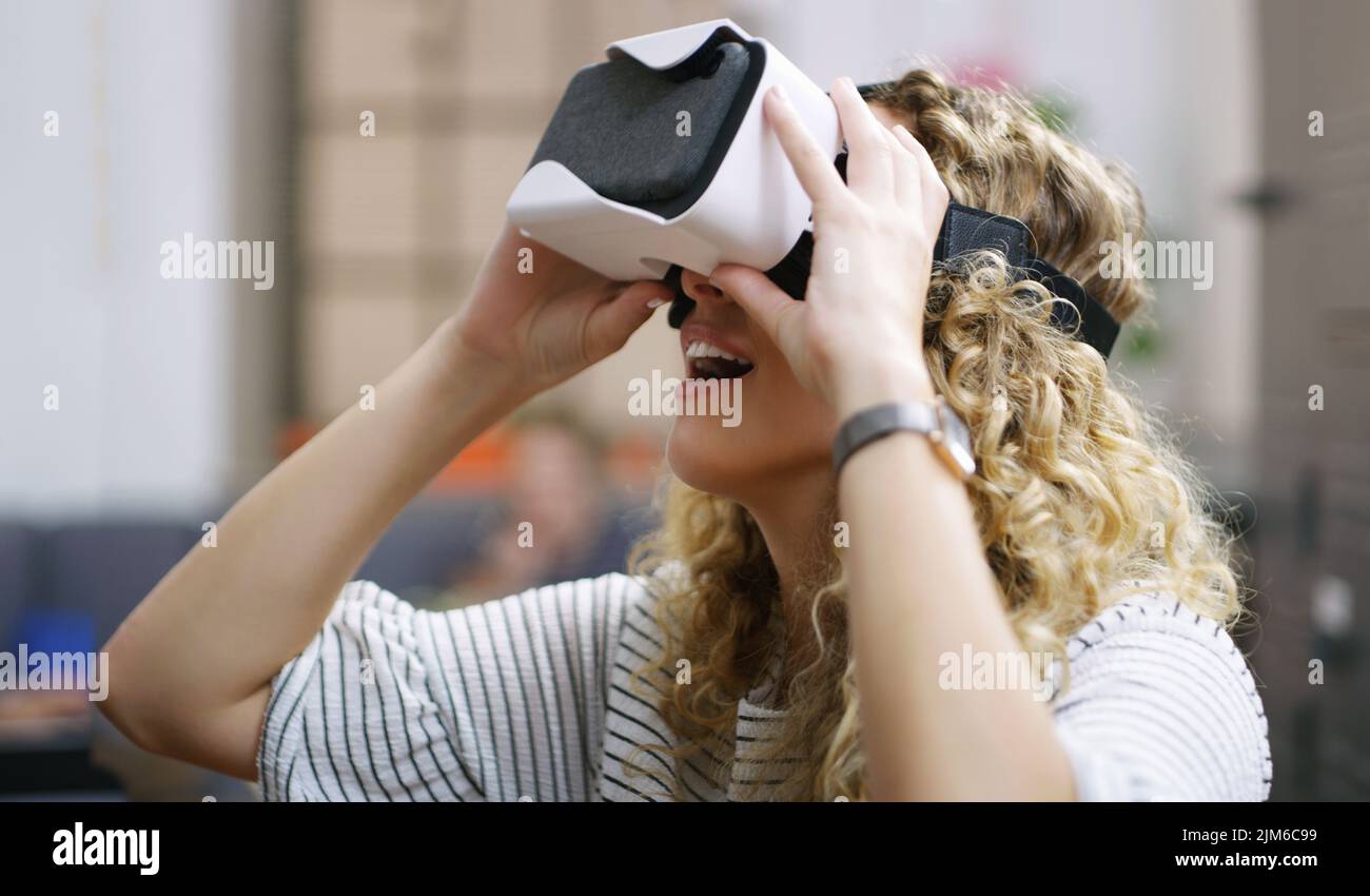 WOW sembra così reale. Una giovane donna d'affari che usa una cuffia per realtà virtuale in un ufficio moderno. Foto Stock