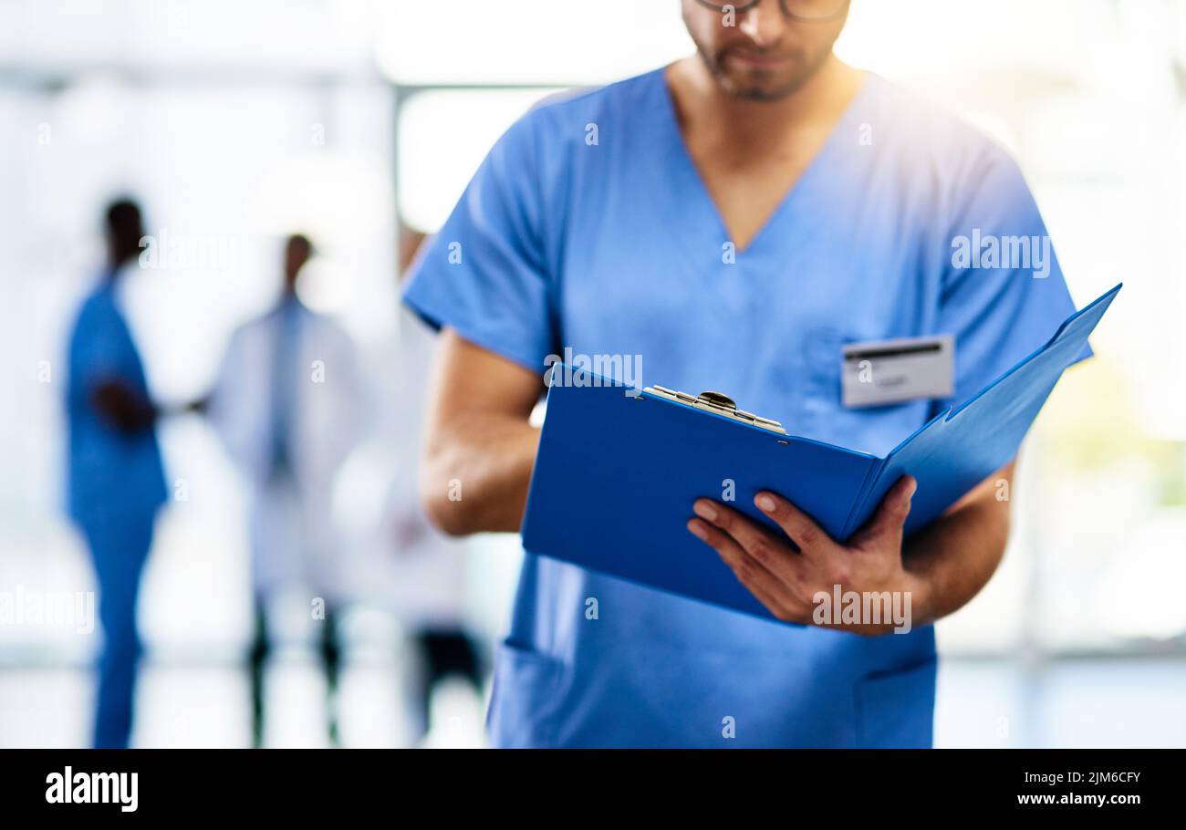 Medico, medico e lavoratore che legge da un file, cartella o forma mentre lavora in un ospedale moderno. Analisi infermiere, chirurgo o gp Foto Stock