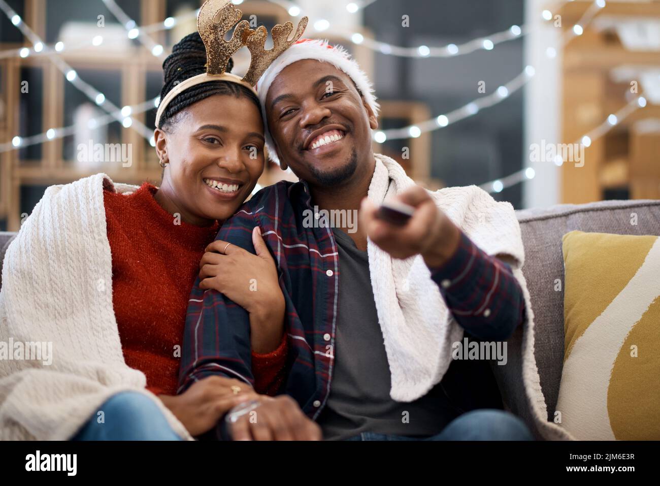 Il tutto accogliente e pronto a godere del miglior intrattenimento per le vacanze. Ritratto di una giovane coppia che guarda la televisione mentre festeggia il Natale a casa. Foto Stock
