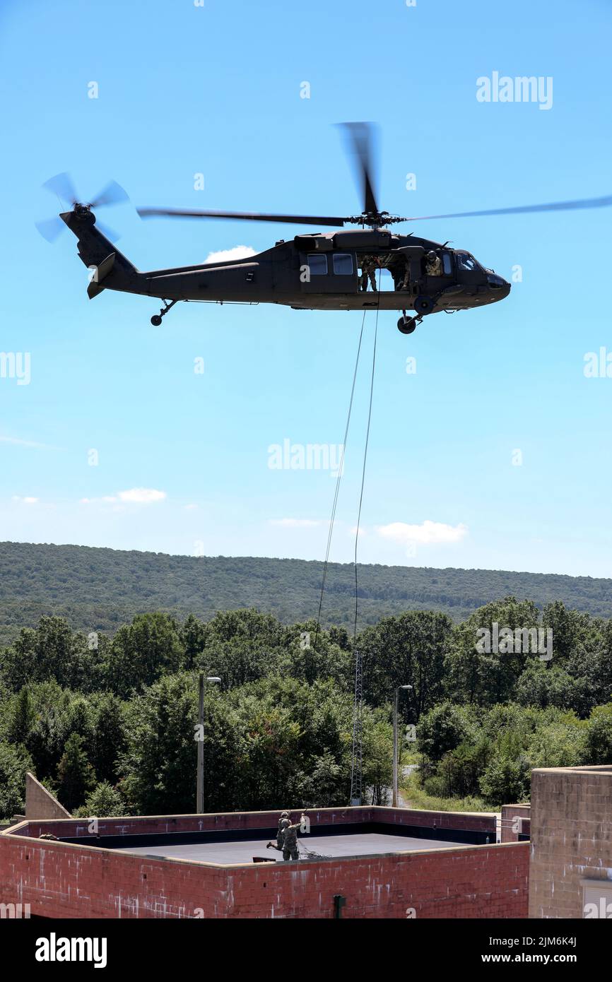 Soldiers with Headquarters and Headquarters Company, 1st battaglione, 110th reggimento fanteria, 28th divisione fanteria, dispiegano linee belay da un falco nero UH-60 della brigata aerea di combattimento 28th durante una missione di addestramento di rapelling a Fort Indiantown Gap, Pa., il 3 agosto 2022. I soldati hanno eseguito diverse gocce di rapel dal falco nero in un campo in preparazione per il dispiegamento sull'edificio. La pianificazione e la preparazione per l'addestramento verifica che i soldati siano pronti a svolgere il compito in modo sicuro e secondo gli standard. (STATI UNITI Foto dell'esercito dello staff Sgt. Brandon Nelson) Foto Stock