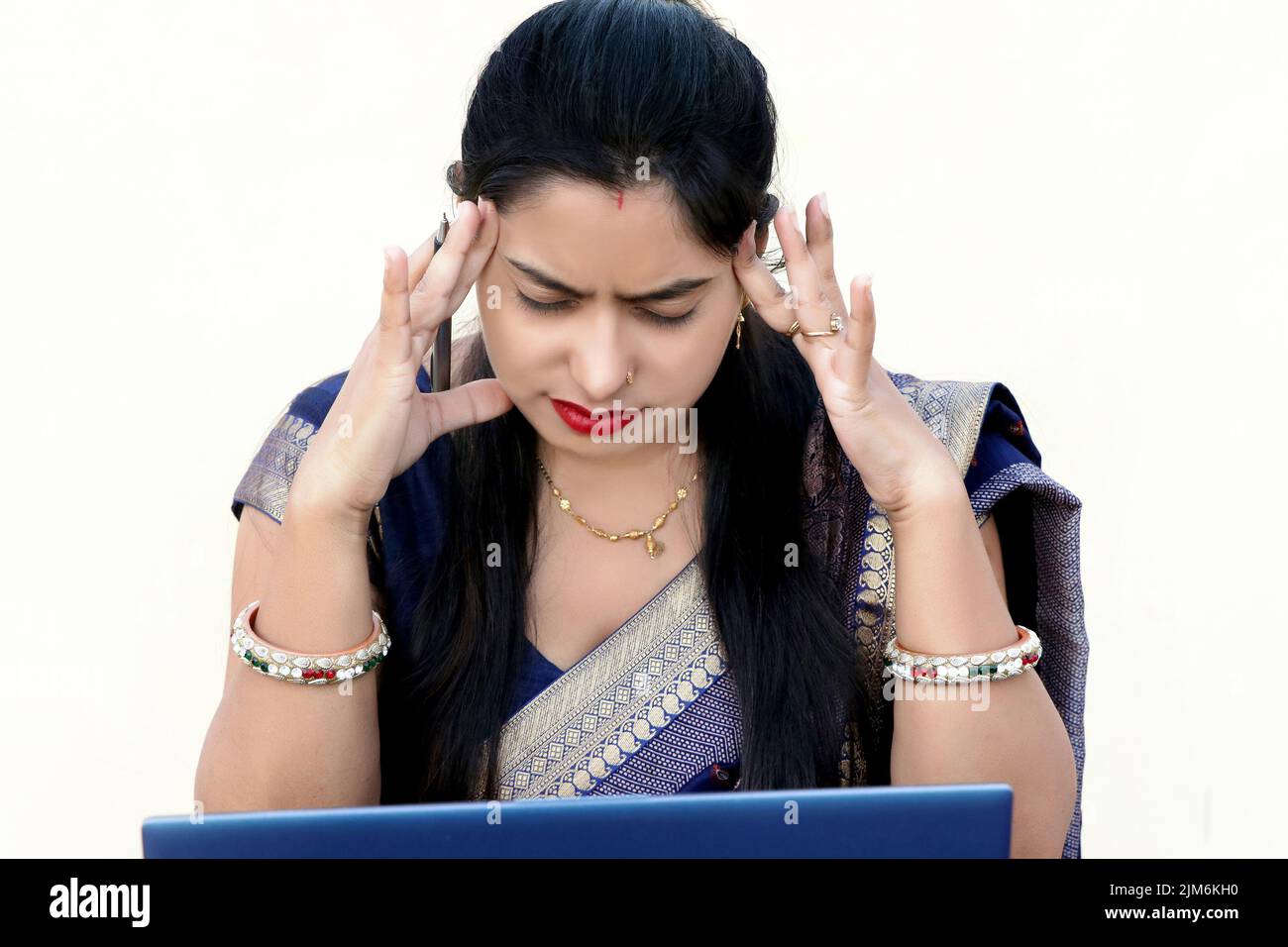 Una donna indiana che lavora su un notebook con mal di testa Foto Stock