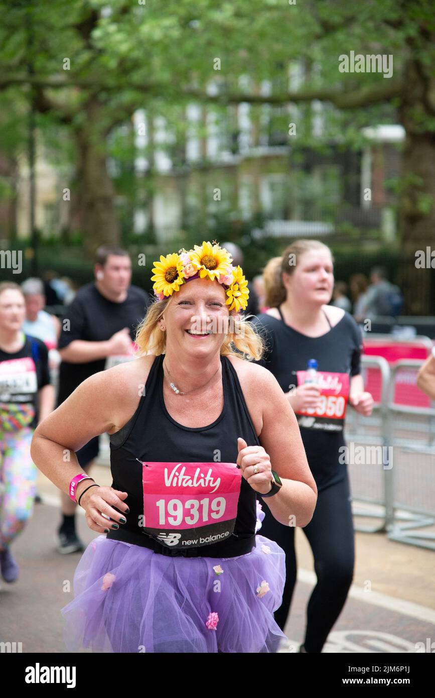 Un'immagine verticale di una runner femminile in un tutu viola con fascia girasole durante il Vitality London 10000 Foto Stock