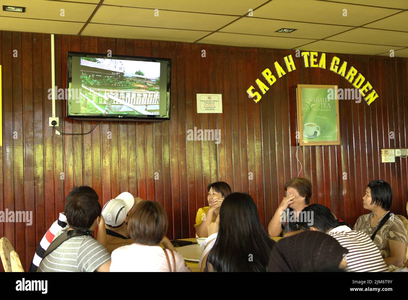 Un gruppo di turisti seduti intorno ad un tavolo presso la caffetteria della fabbrica di tè Sabah, una parte del giardino del tè Sabah a Sabah, Malesia. Foto Stock