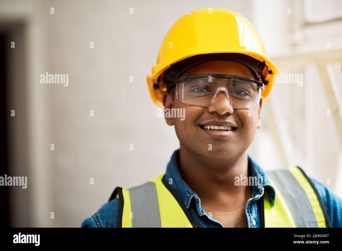 I lavori di costruzione richiedono un adeguato equipaggiamento di sicurezza. Un tecnico che indossa un equipaggiamento di protezione su un cantiere. Foto Stock