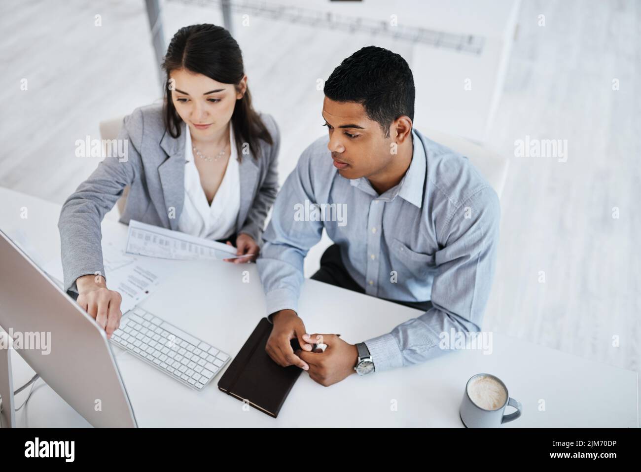 Una cultura del lavoro collaborativo mantiene alta la qualità: Un giovane uomo d'affari e una donna d'affari che usano un computer in un ufficio moderno. Foto Stock