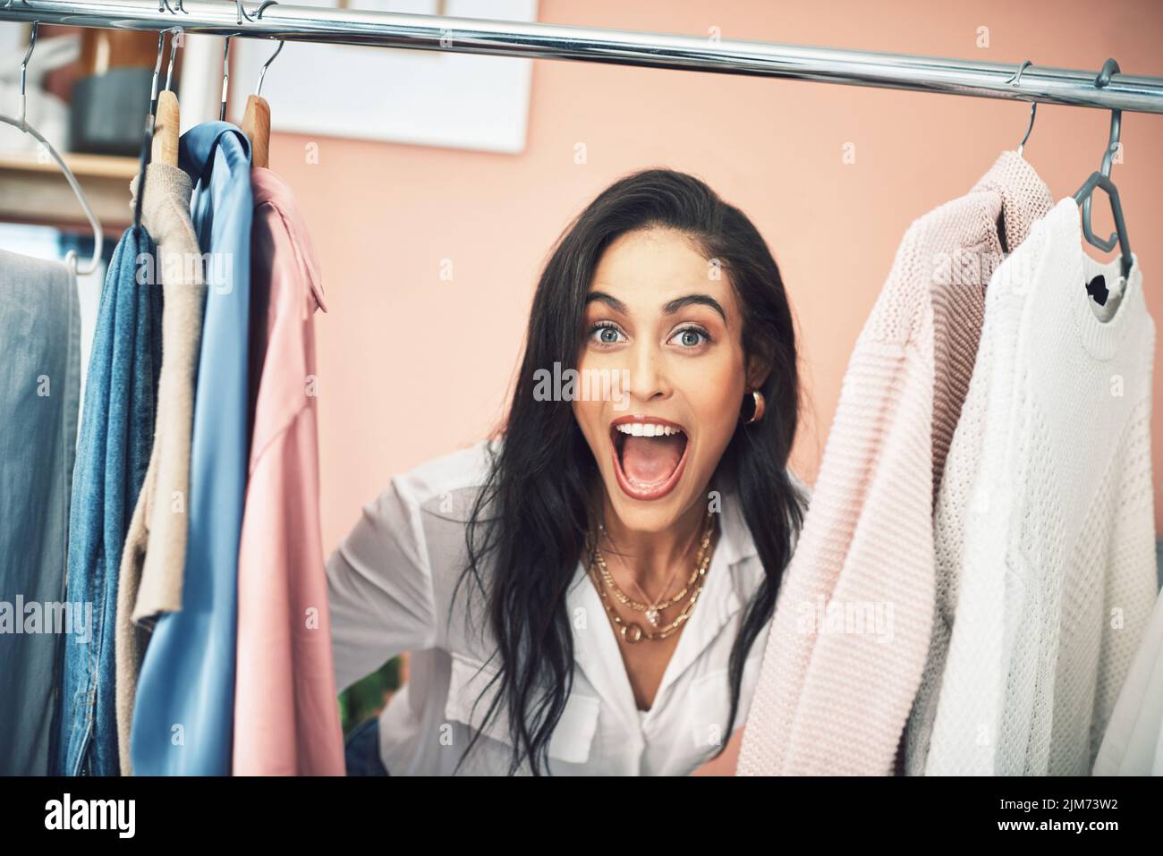 Oggi im lasciando i miei seguaci nel mio guardaroba. Una giovane donna che si appica la testa tra gli oggetti su una barra di abbigliamento. Foto Stock