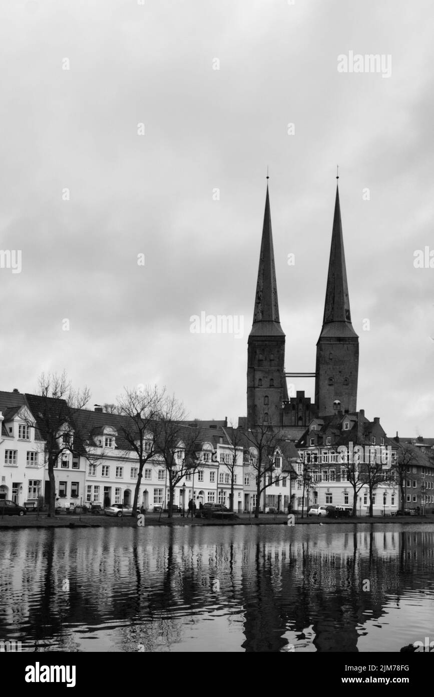 Uno scatto verticale in scala di grigi della chiesa di Santa Maria riflessa sul fiume trave Foto Stock