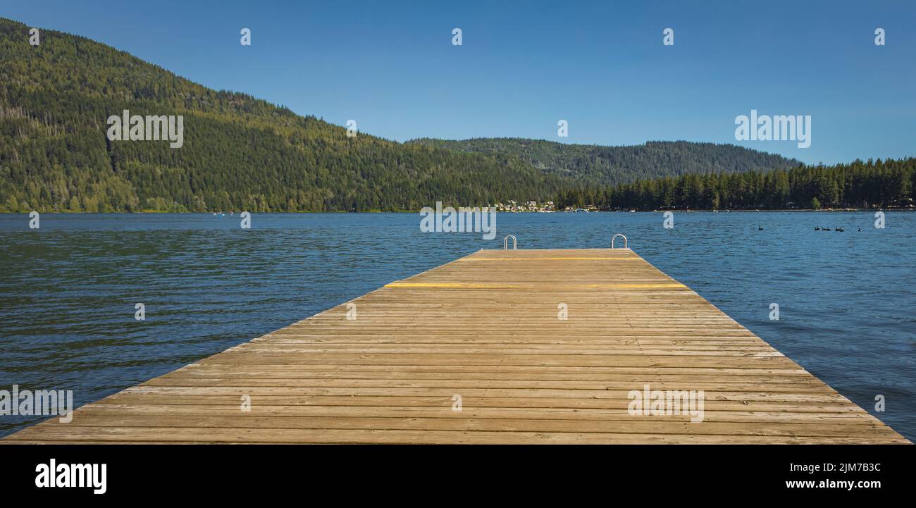 Molo in legno con scala in metallo nel mare, lago, acqua. Molo per il nuoto con scala in metallo sul lago blu calmo in giornata di sole sull'idilliaco resort di Cult Foto Stock