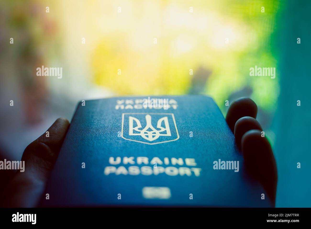 Passaporto biometrico ucraino in primo piano su sfondo sfocato. Stemma dell'Ucraina sotto forma di tridente. Documento blu di prova di identificazione Foto Stock