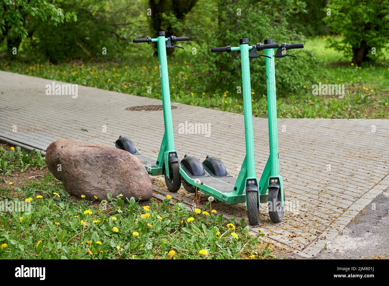 Un primo piano di tre scooter elettrici a noleggio su un sentiero nel parco Rataje Foto Stock