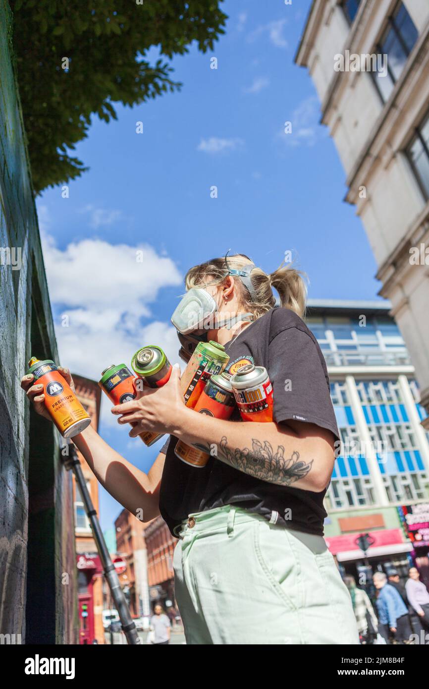 Un artista graffiti al lavoro che dipinge un muro al Manchester Northern Quarter Foto Stock