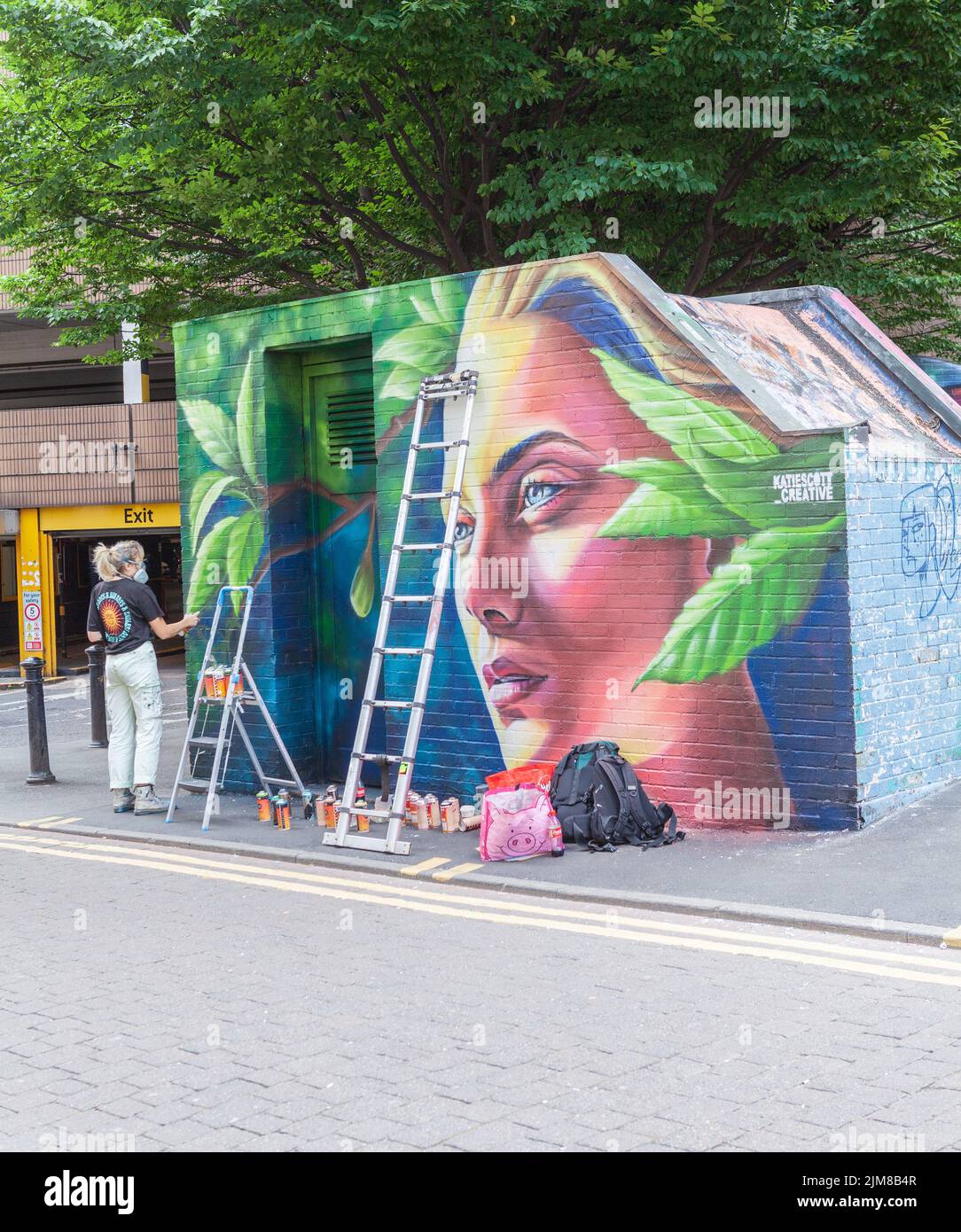 Un artista graffiti al lavoro che dipinge un muro al Manchester Northern Quarter Foto Stock