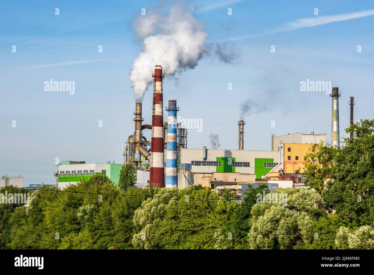 pipe di impresa di lavorazione del legno pianta segheria con bella riflessione in acqua blu del fiume. Concetto di inquinamento atmosferico. Ambienti industriali del paesaggio Foto Stock