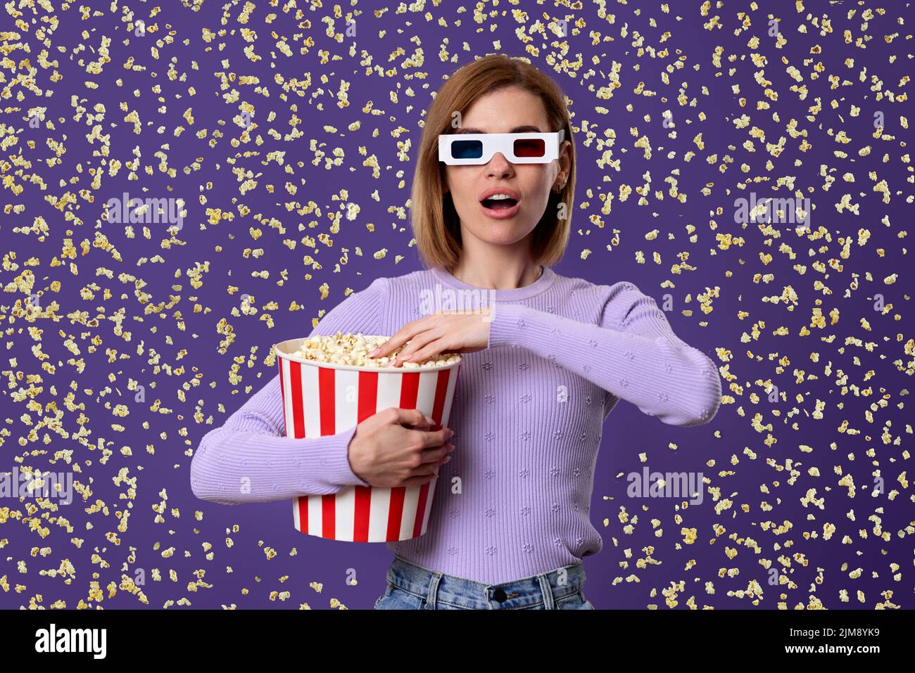 donna che guarda film, che tiene secchio di popcorn Foto Stock