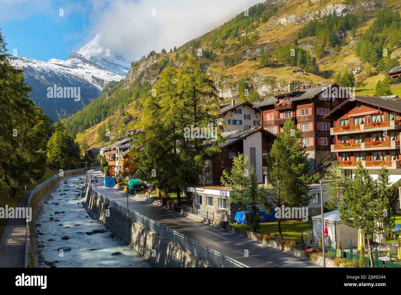Zermatt, Svizzera - 7 ottobre 2019: Vista sulla strada della città nella famosa stazione sciistica delle Alpi svizzere, sul fiume, sulla cima del monte della neve del Cervino Foto Stock