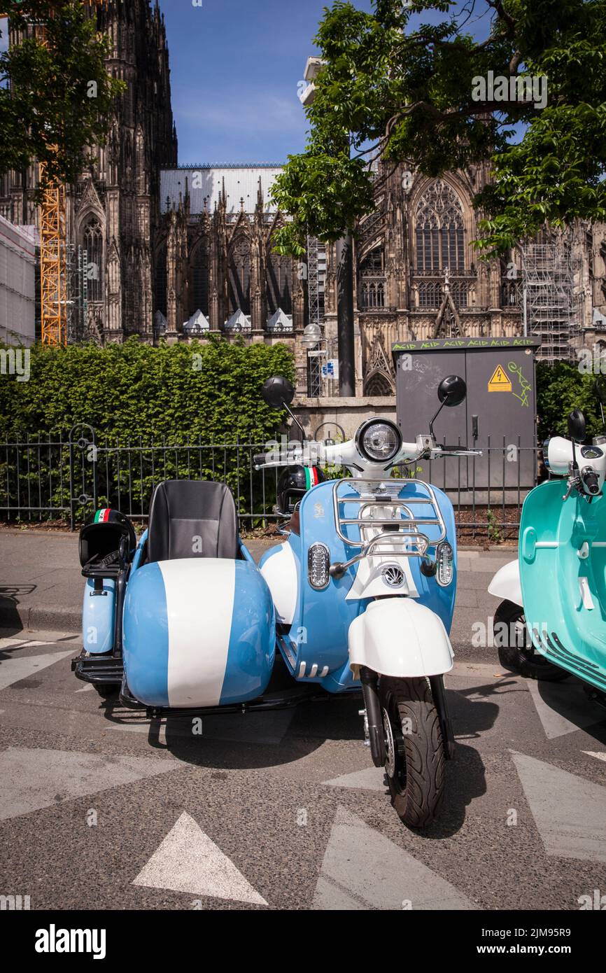 Gli scooter e-Vespina con sidecar sono disponibili in affitto per gite in città vicino alla cattedrale, Colonia, Germania. E-Vespina Roller mit Seitenwagen stehen z Foto Stock