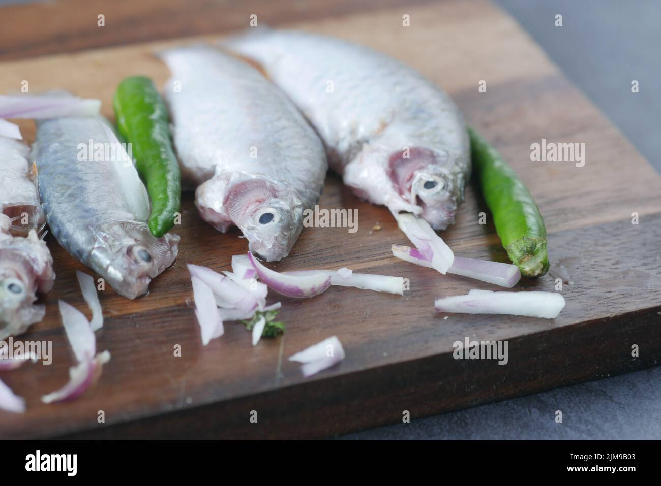 piccoli pesci freschi crudi su un tagliere per preparare la cottura a tavola , Foto Stock