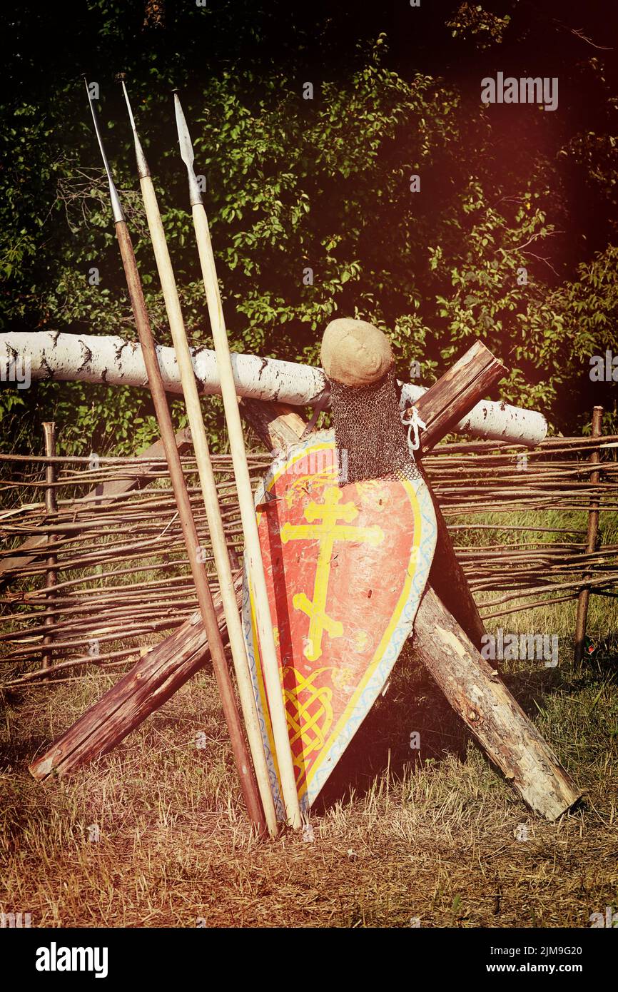 Samara, Russia, la festa della ricostruzione storica antica Russia età 11-13 - 11 agosto 2013 - tre lance, uno scudo con una croce ortodossa con un casco e una catena di posta sul vimini recinto sul campo vicino alla foresta Foto Stock