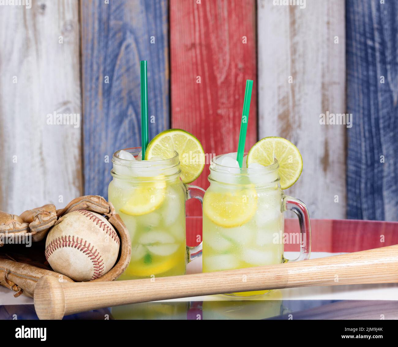 Vasetti di vetro riempiti di limonata fredda insieme a oggetti sportivi di baseball sui colori nazionali degli Stati Uniti per la stagione di festa Foto Stock