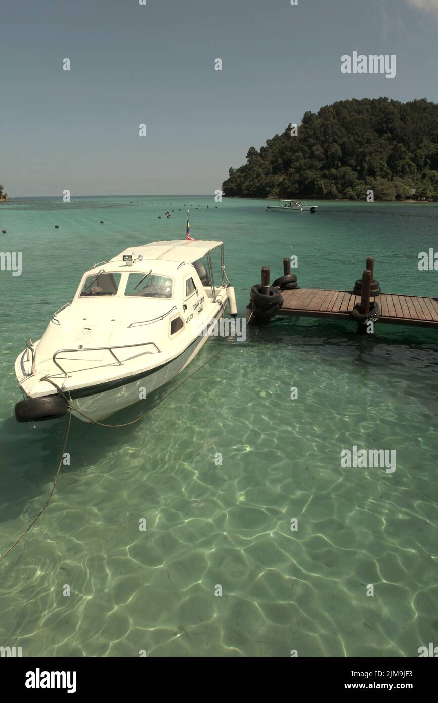 Una barca turistica sull'acqua costiera, vista da un molo su Pulau Sapi (Isola Sapi), una parte del Parco Tunku Abdul Rahman a Sabah, Malesia. Foto Stock