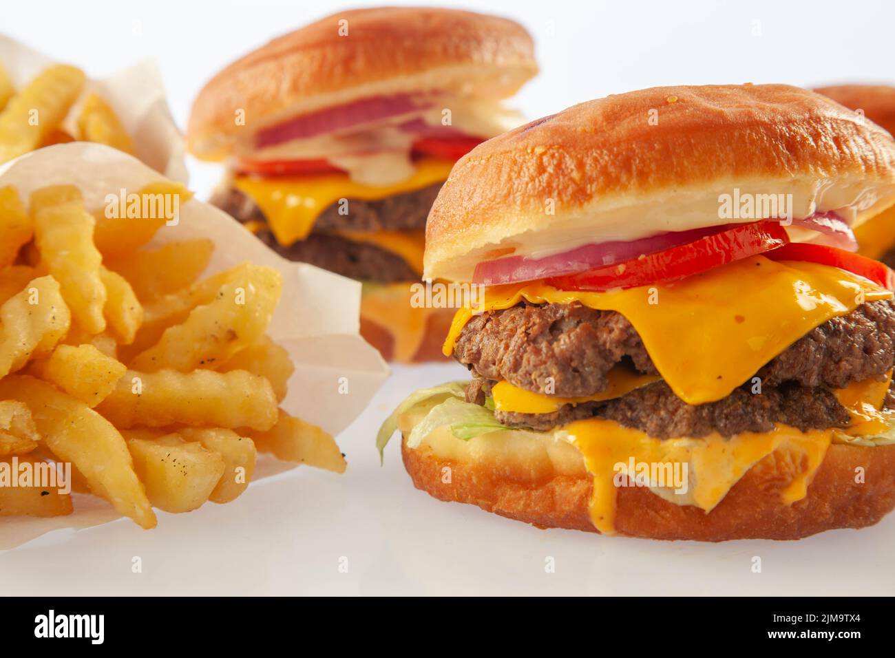 Brioche donut doppio hamburger di manzo al piano con salsa queso con un altro hamburger sullo sfondo. Foto Stock