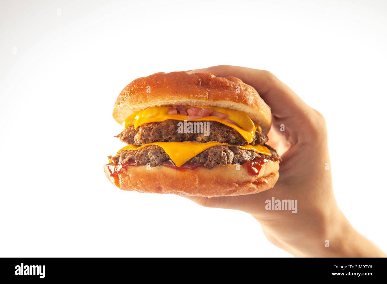Mano che tiene un hamburger di formaggio brioche gourmet con salsa di queso isolato su uno sfondo bianco Foto Stock