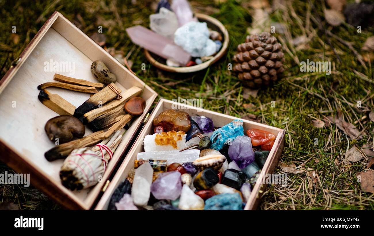 Un primo piano di pietre di cristallo, coni di pino e bastoni di legno per rituali. Concetto di guarigione olistica e di energia spirituale Foto Stock