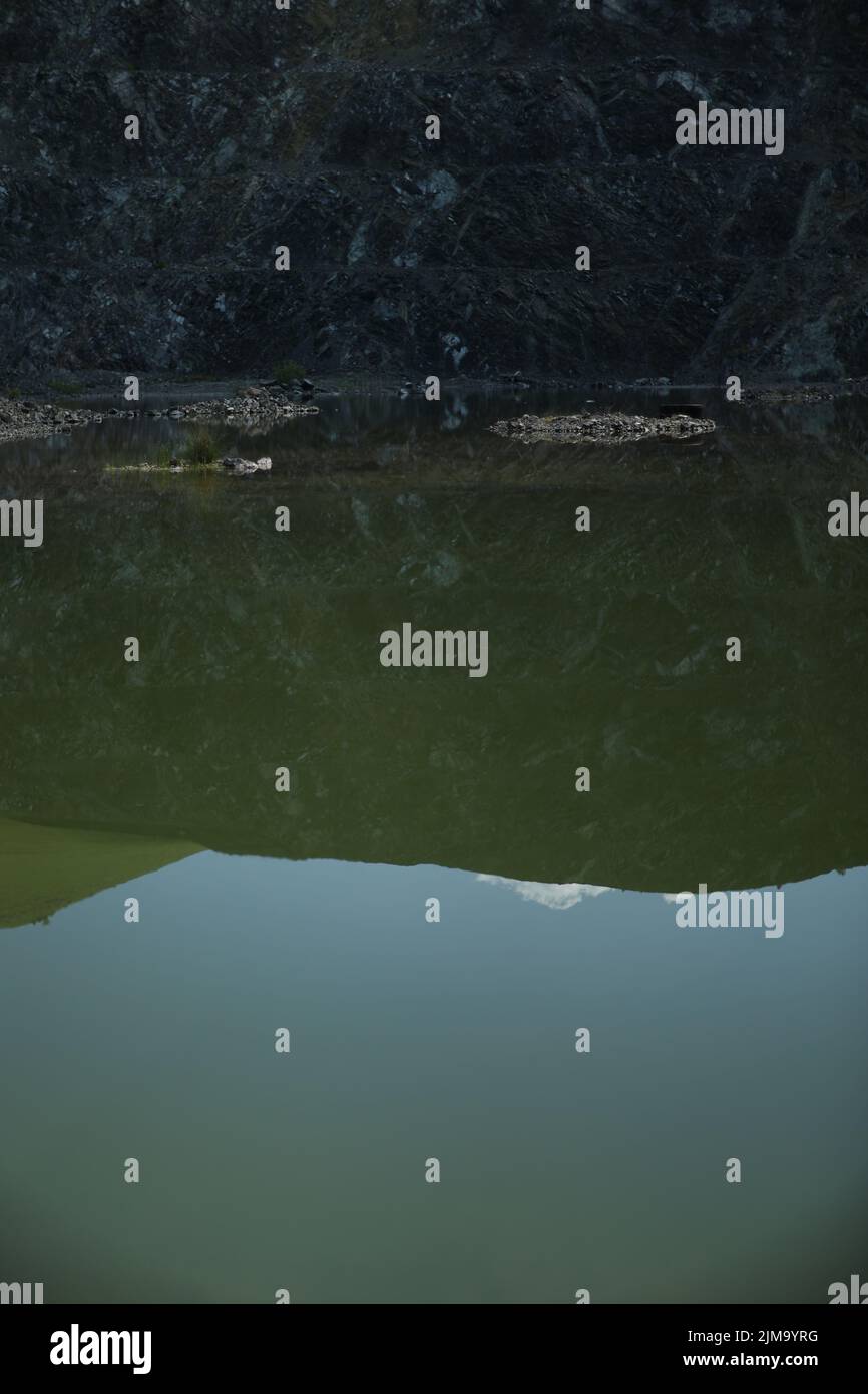 Un colpo verticale di un lago con il riflesso della montagna con le sue stratas Foto Stock