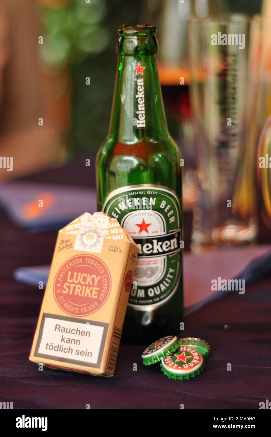 Una scatola di sigarette Lucky Strike senza additivi davanti a una bottiglia di birra Heineken Foto Stock