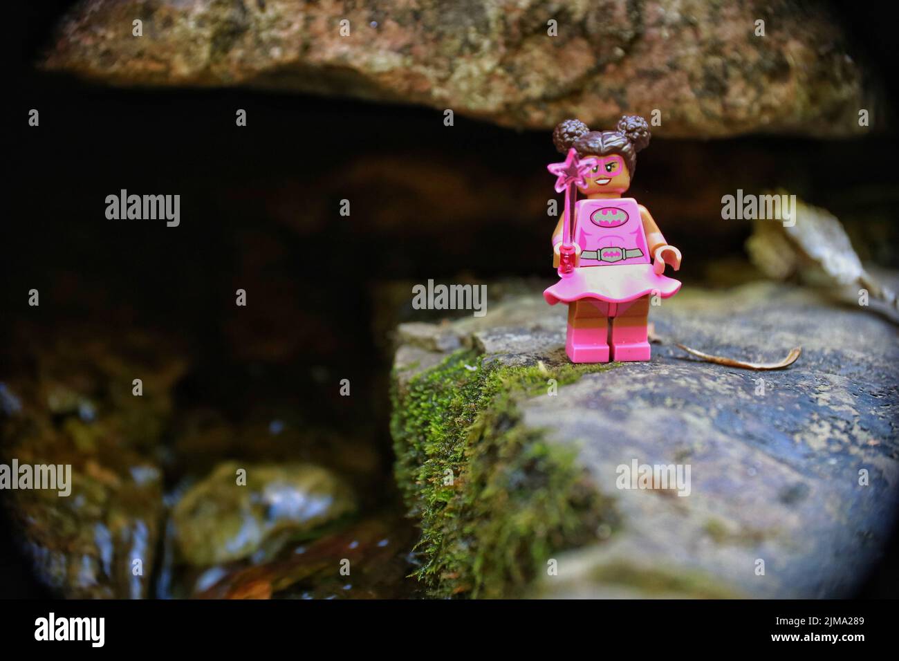 LEGO giocattolo di una donna eroe in piedi su una roccia che regge una stella bacchetta Foto Stock