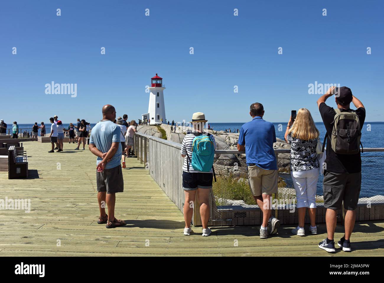 Peggy’s Cove, Canada - 31 luglio 2022: La gente guarda il famoso faro di Peggy’s Cove. Una piattaforma di osservazione in legno è stata installata nel 2021 per dare peopl Foto Stock